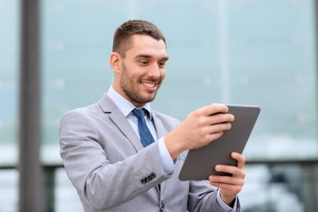 A man holding his Ipad while wearing a suit