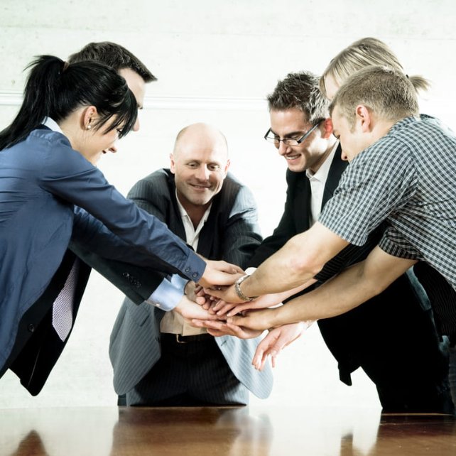 a team putting their hands together at a meeting table