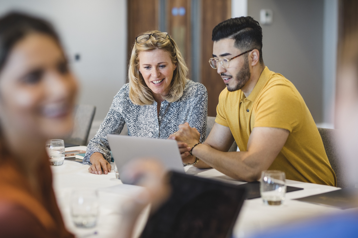 hipster young man showing female colleague laptop