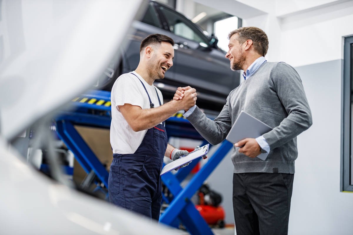happy auto mechanic and his manager greeting